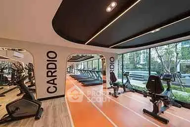 Modern gym with cardio equipment and large windows in upscale residential complex.