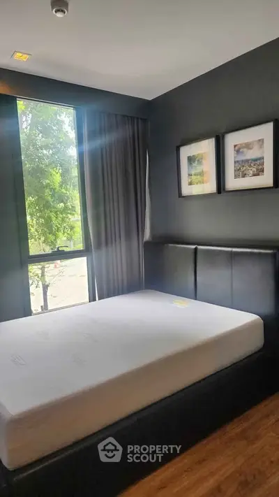 Modern bedroom with large window and stylish decor in a contemporary apartment.