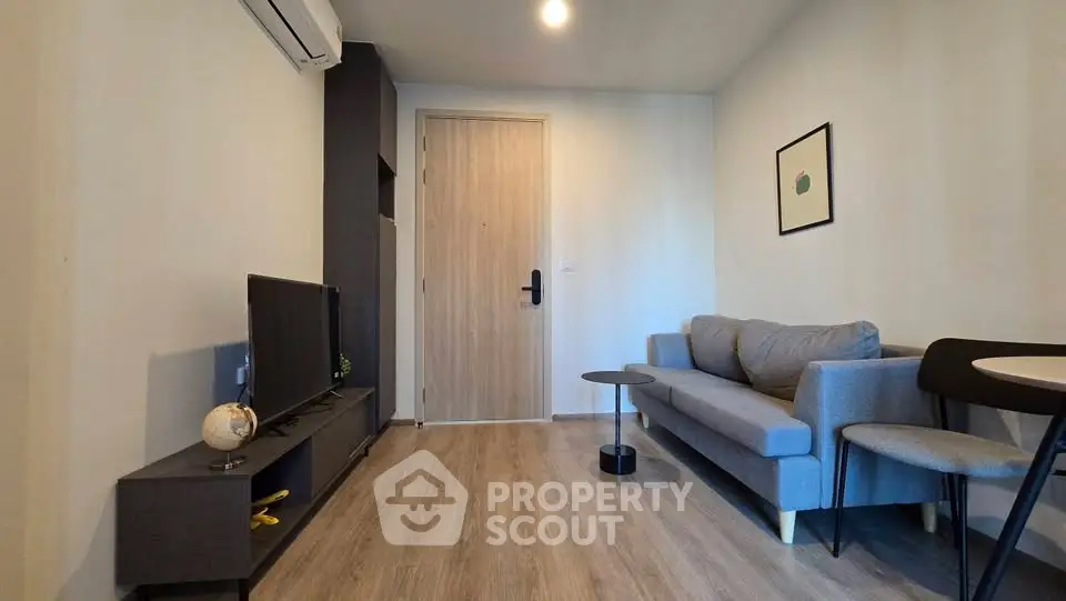 Modern living room with sleek furniture and wooden flooring, featuring a cozy sofa and flat-screen TV.