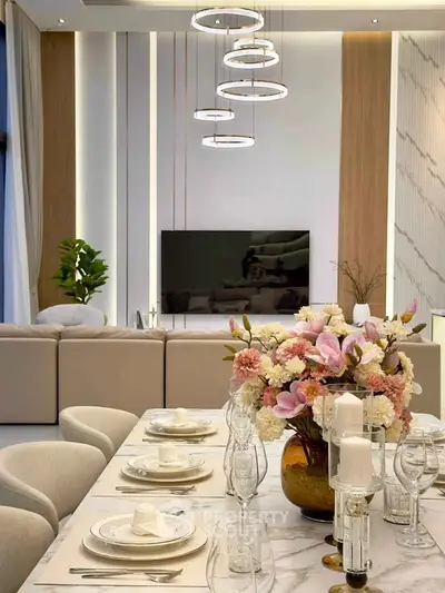 Luxurious modern living room with elegant dining setup and stylish lighting fixtures.
