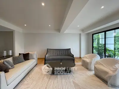 Spacious modern living room with elegant furniture and large windows overlooking greenery.