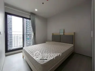 Modern bedroom with large window and city view in high-rise apartment