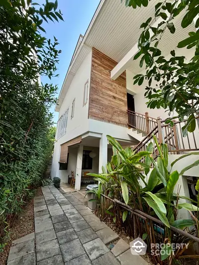 Charming two-story house with lush garden pathway and wooden accents