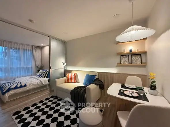 Modern open-plan living room with cozy dining area and stylish bedroom view.