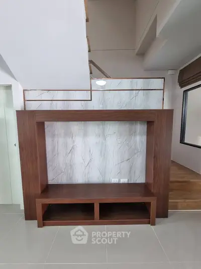 Modern interior with stylish wooden TV stand and marble accent wall