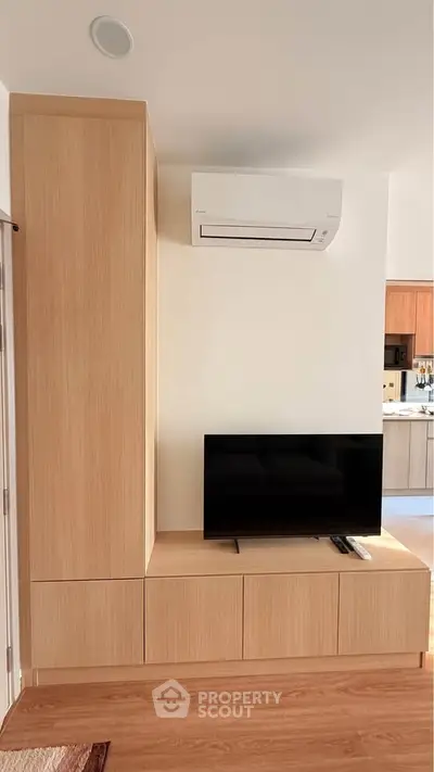 Modern living room with sleek wooden TV unit and air conditioning, showcasing minimalist design.
