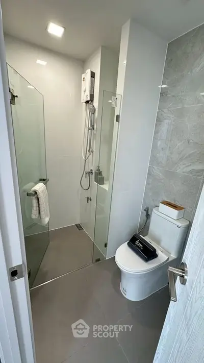Modern bathroom with glass shower enclosure and sleek fixtures in a contemporary apartment.