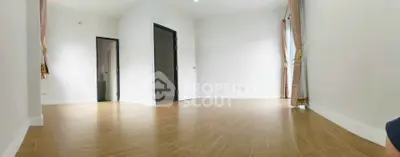 Spacious empty room with wooden flooring and large windows for natural light.