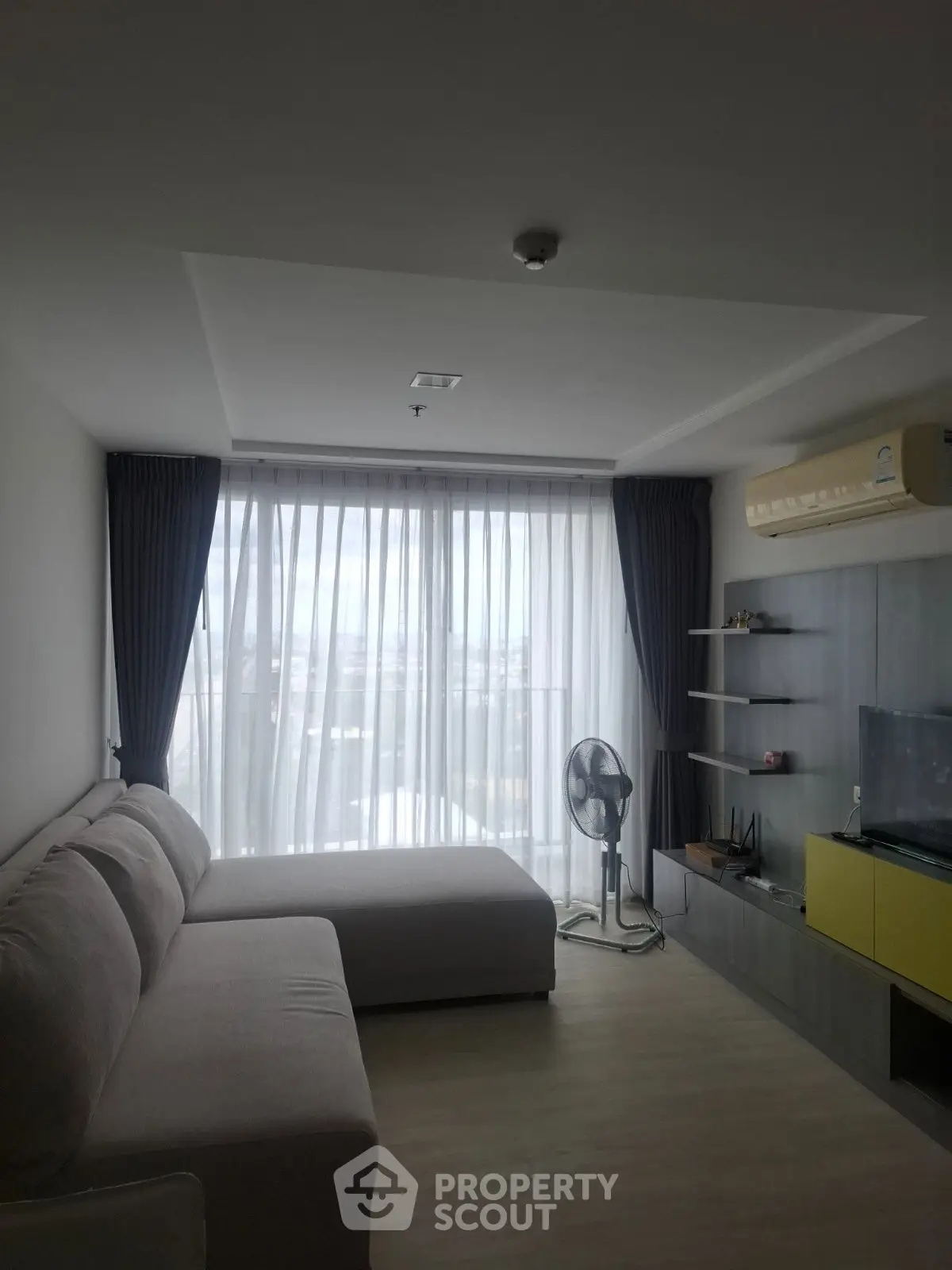 Modern living room with large window, cozy sofa, and sleek entertainment unit.