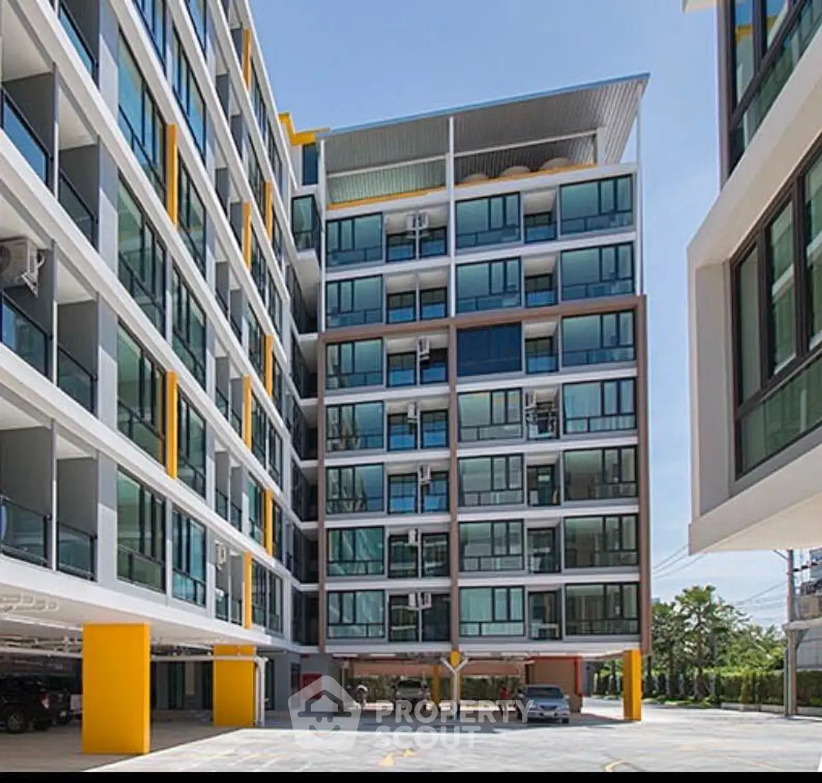 Modern apartment building exterior with large windows and vibrant yellow accents.