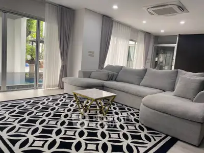 Spacious living room with modern decor and pool view, featuring a stylish gray sofa and geometric rug.