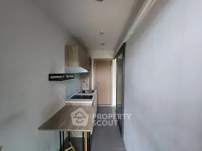 Compact kitchen with modern fixtures and wooden cabinetry in a sleek apartment.