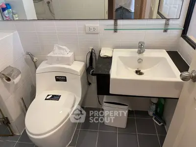Modern bathroom with sleek fixtures and contemporary design, featuring a stylish sink and toilet.