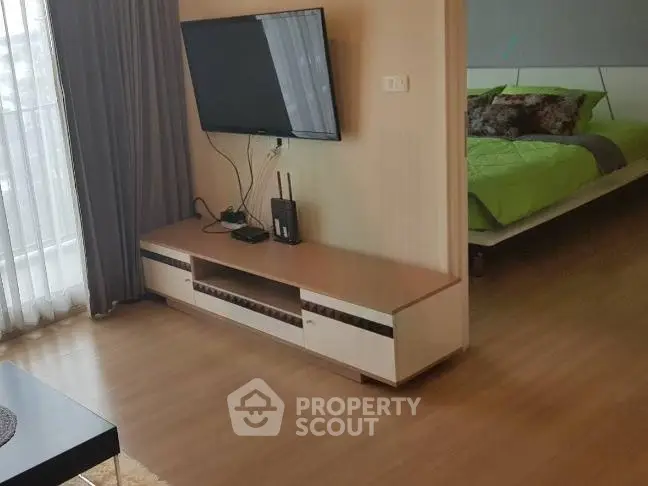 Modern living room with wall-mounted TV and view into stylish bedroom