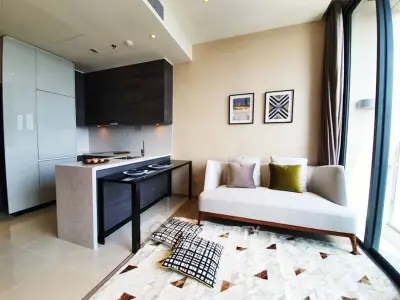 Modern living room with open kitchen, stylish decor, and large windows for natural light.