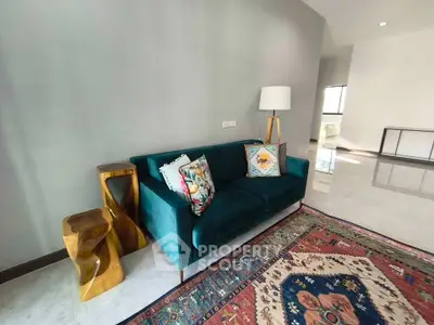 Stylish living room with modern teal sofa and vibrant rug in a contemporary home.
