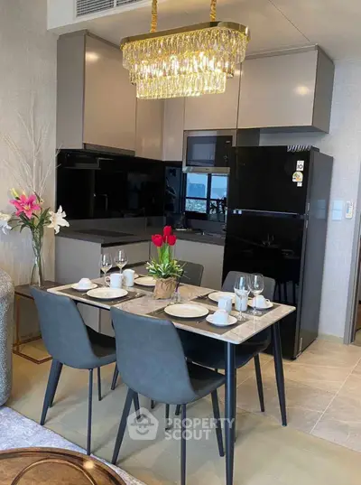 Modern kitchen with elegant dining setup and stylish chandelier in a cozy apartment.