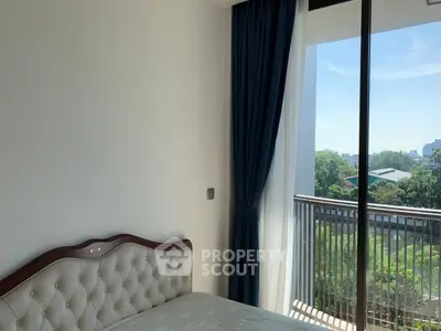 Bright bedroom with elegant headboard and large window offering scenic view of greenery.