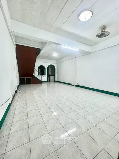 Spacious tiled interior with staircase and ceiling fan, ideal for versatile living space.
