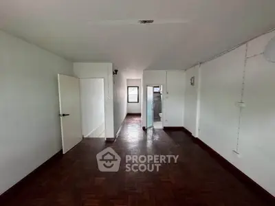 Spacious empty room with wooden flooring and white walls, ideal for customization.