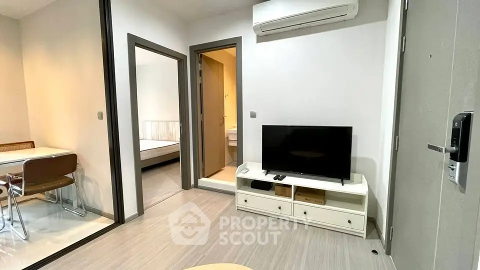 Modern apartment interior with living room, dining area, and bedroom access, featuring sleek design and air conditioning.