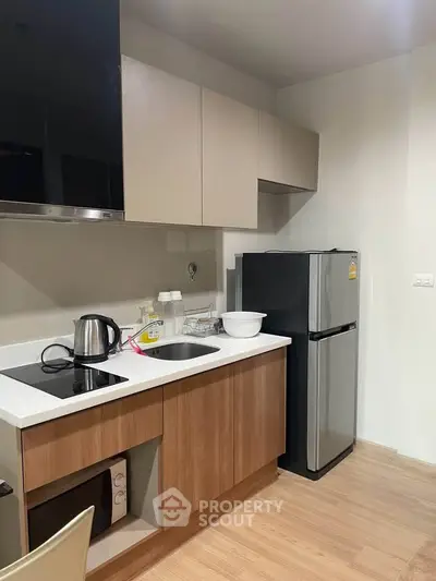 Modern kitchen with sleek appliances and wooden cabinetry in a stylish apartment.