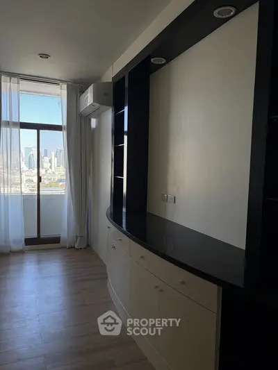 Spacious living room with built-in shelves and city view from large window.