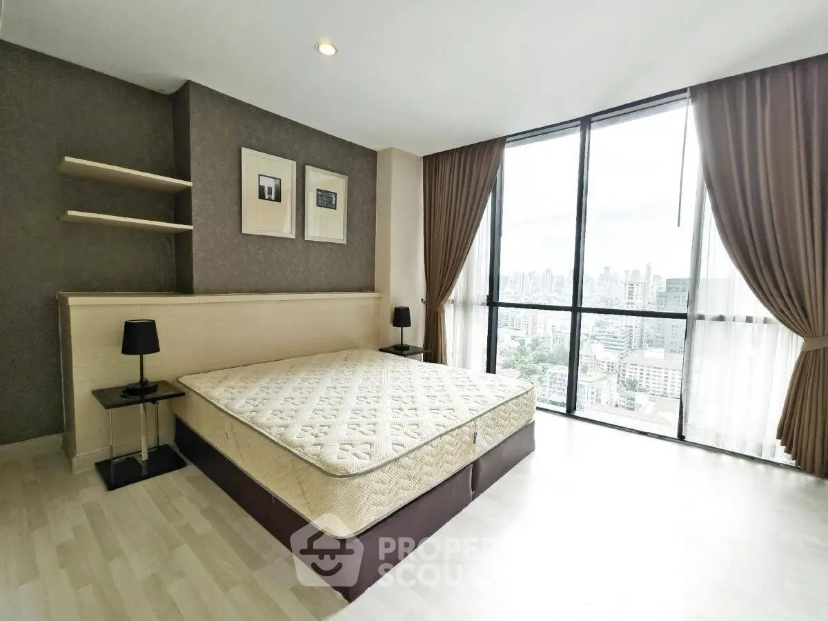 Spacious bedroom with large windows offering stunning city views in modern apartment.