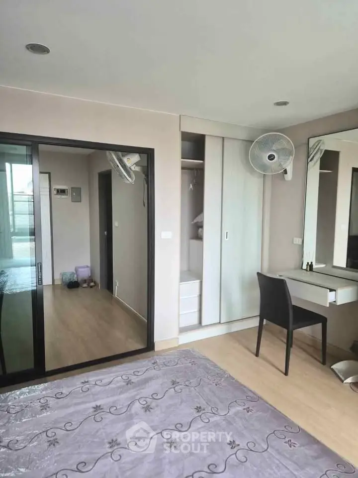 Modern bedroom with sliding closet doors and vanity desk, featuring a sleek design and ample natural light.