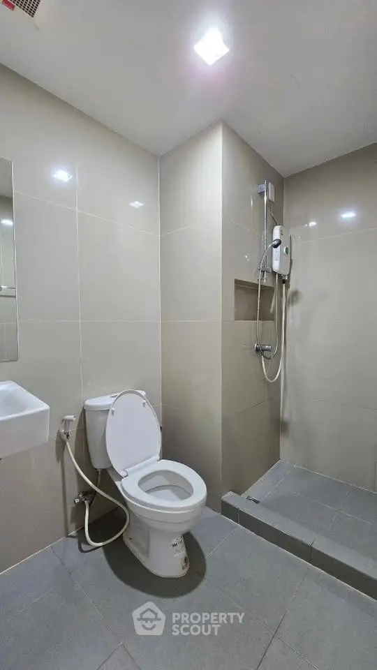 Modern bathroom with sleek tiles and walk-in shower in contemporary home.