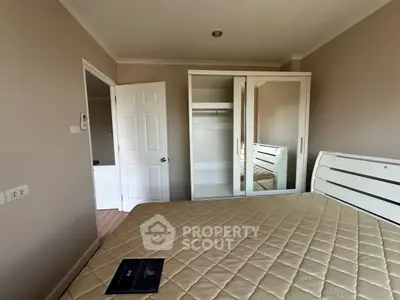Spacious bedroom with mirrored wardrobe and cozy bed in modern apartment.