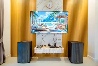 Modern living room with stylish decor and entertainment setup featuring large TV and speakers.
