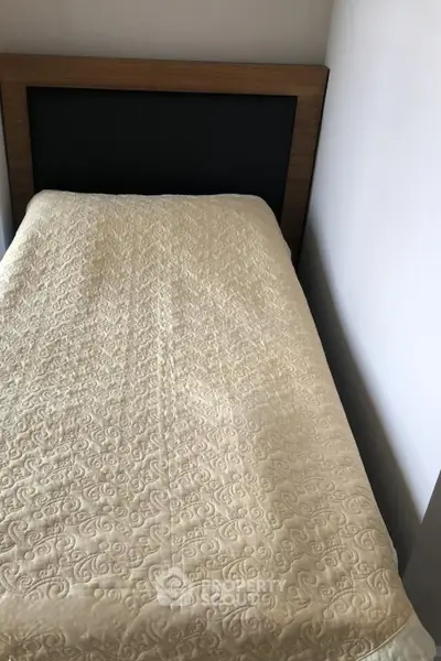 Cozy bedroom with a single bed and elegant headboard, perfect for a minimalist living space.
