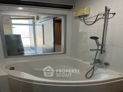 Modern bathroom with corner bathtub and shower in sleek apartment.