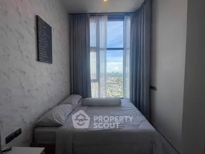 Cozy bedroom with large window offering stunning city view, modern decor, and comfortable bedding.