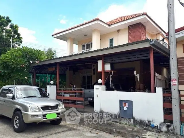 Charming two-story house with carport and lush greenery in a serene neighborhood.