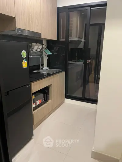 Modern kitchen with sleek black fridge and open layout in stylish apartment.