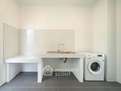 Modern laundry room with sleek sink and washing machine in minimalist design.