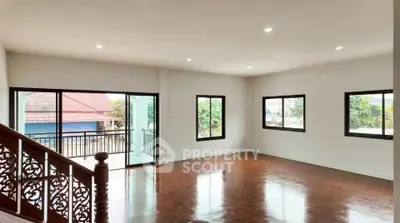 Spacious living room with polished wooden floors and large windows offering natural light.