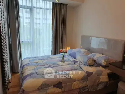 Cozy bedroom with modern decor and large window offering natural light.