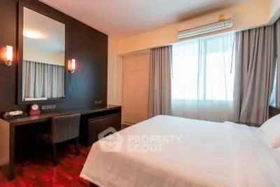 Spacious bedroom with modern decor and natural light, featuring a comfortable bed and stylish furnishings.