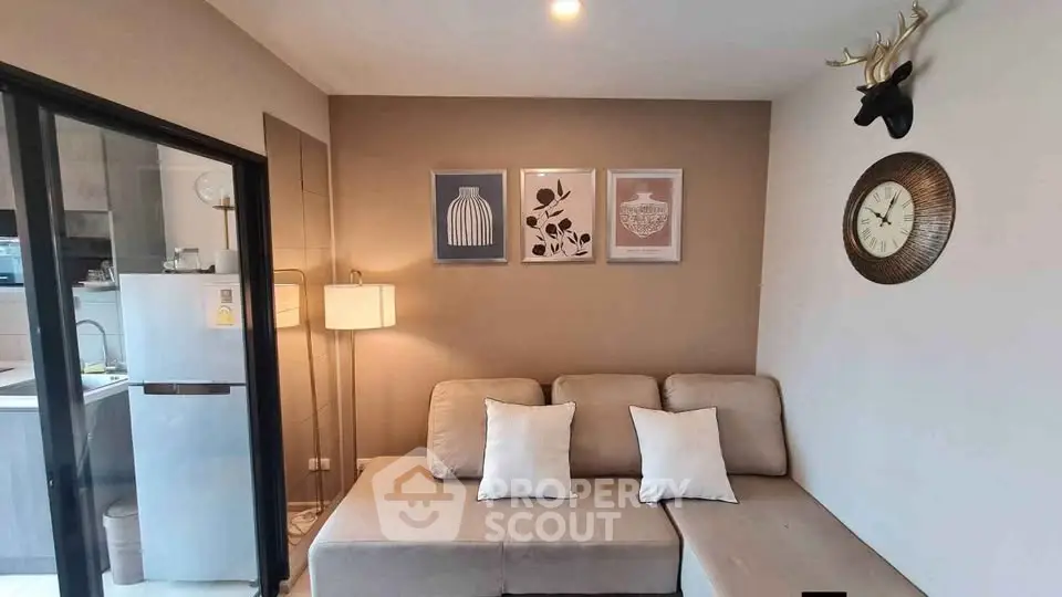 Modern living room with cozy beige sofa and stylish decor, adjacent to a sleek kitchen area.