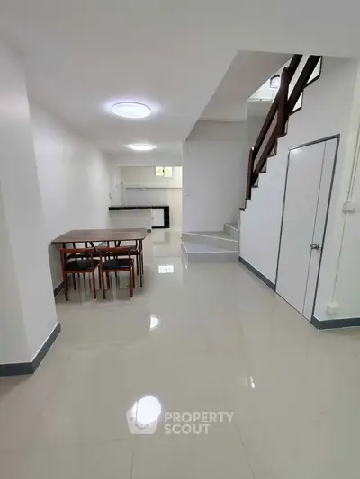 Spacious open-plan living area with modern staircase and dining set.