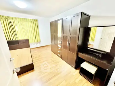 Spacious bedroom with wooden flooring and modern furniture, perfect for comfort and style.