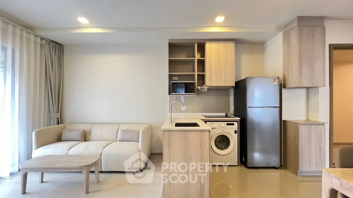 Modern open-plan living room with kitchen, featuring sleek appliances and cozy seating area.