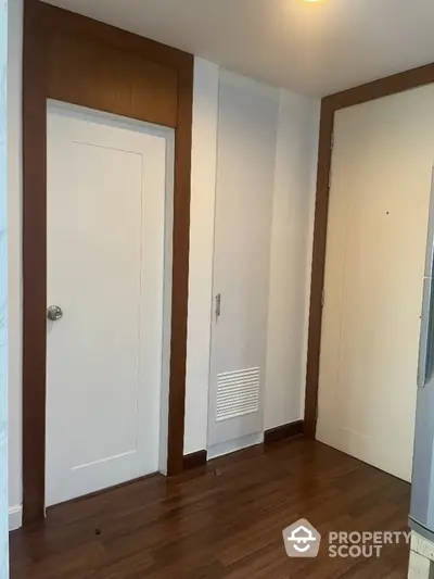 Modern apartment entrance with wooden flooring and white doors