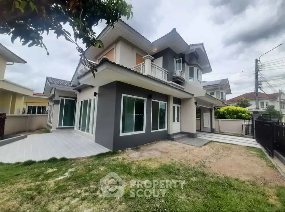 Modern two-story house with large windows and spacious yard in suburban neighborhood.