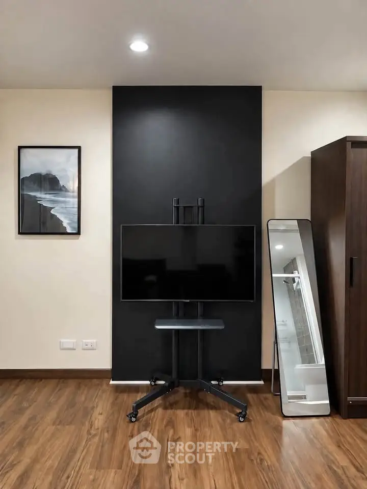 Modern interior with sleek TV stand, full-length mirror, and stylish decor on wooden flooring.