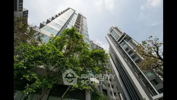 Stunning modern high-rise buildings with lush greenery and clear sky view.