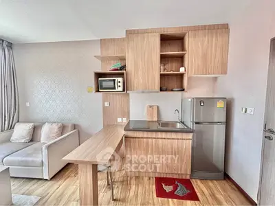 Modern studio apartment with compact kitchen and cozy living area, featuring wood cabinetry and sleek appliances.